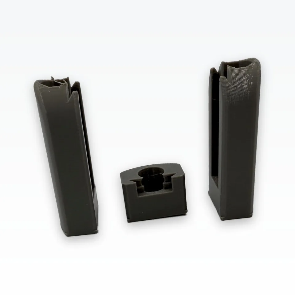 Photo of the two grey PETG finger bodies from the front, the dovetail pad slot running down each, with the mount coupon between them
