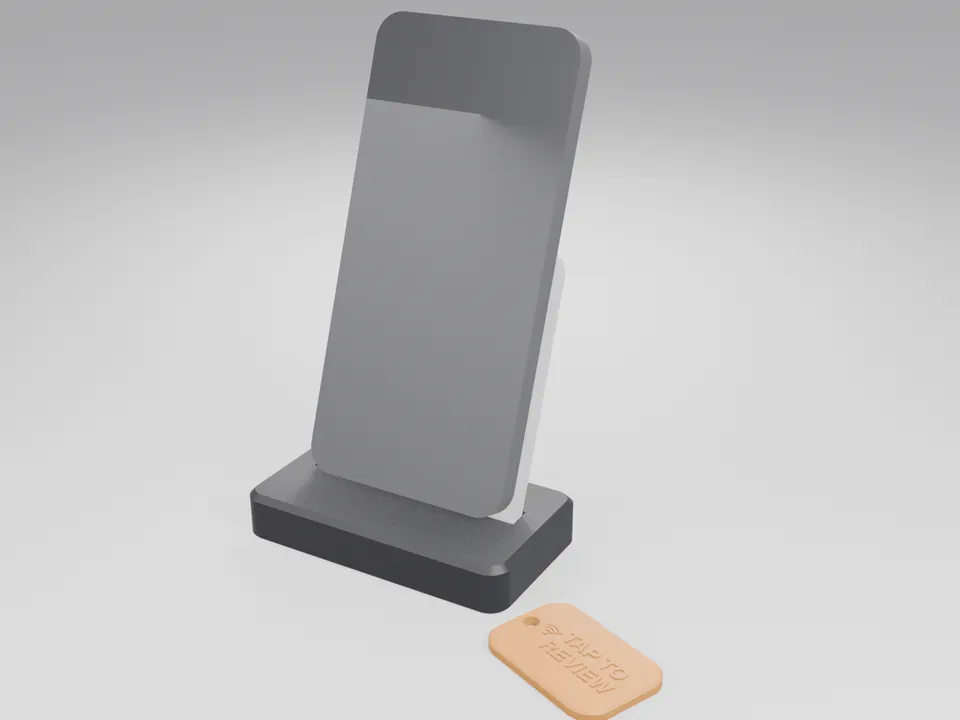 Phone-sized grey block resting on a black and white NFC counter stand, with an orange keyring tag beside it