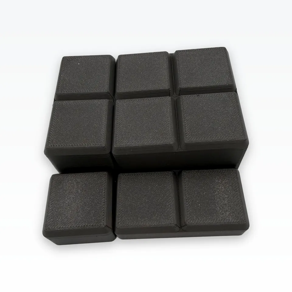 Underside of black 3D printed bins showing the chamfered 42 mm grid feet