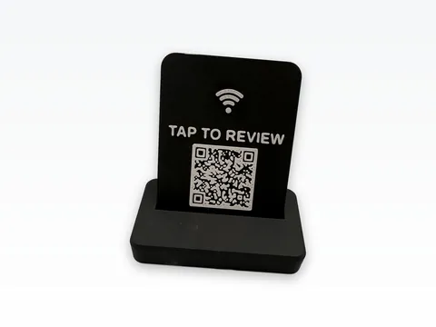 Black 3D printed counter stand holding a black face plate with a white wifi-style tap icon, the words TAP TO REVIEW and a white QR code