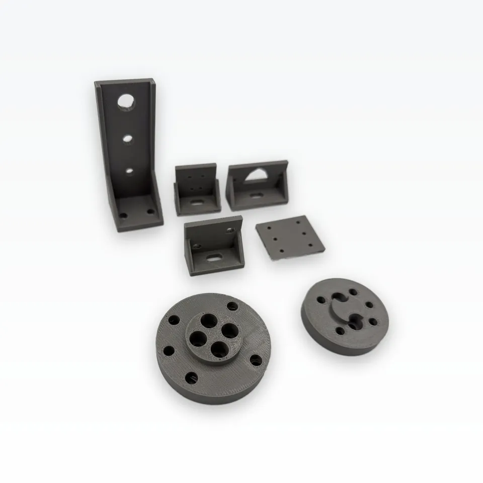Grey 3D printed suction-cup arm, four small brackets, a coupon plate and two round ISO 9409-1 adapters from a higher angle
