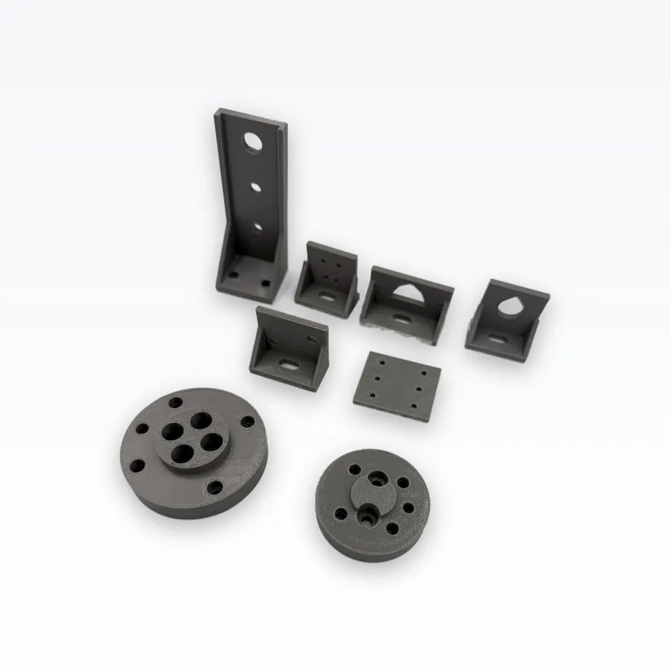 Low-angle view of grey 3D printed robotics brackets and two round flange adapters with a central pilot boss